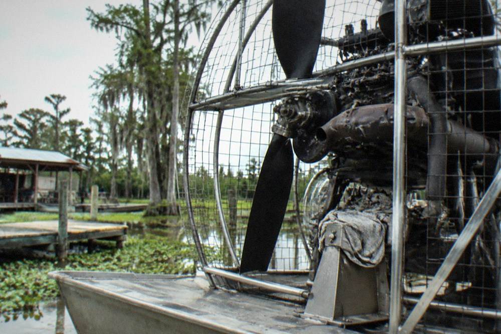 Close view of an airboat's propeller cage and engine mounted above the flat hull