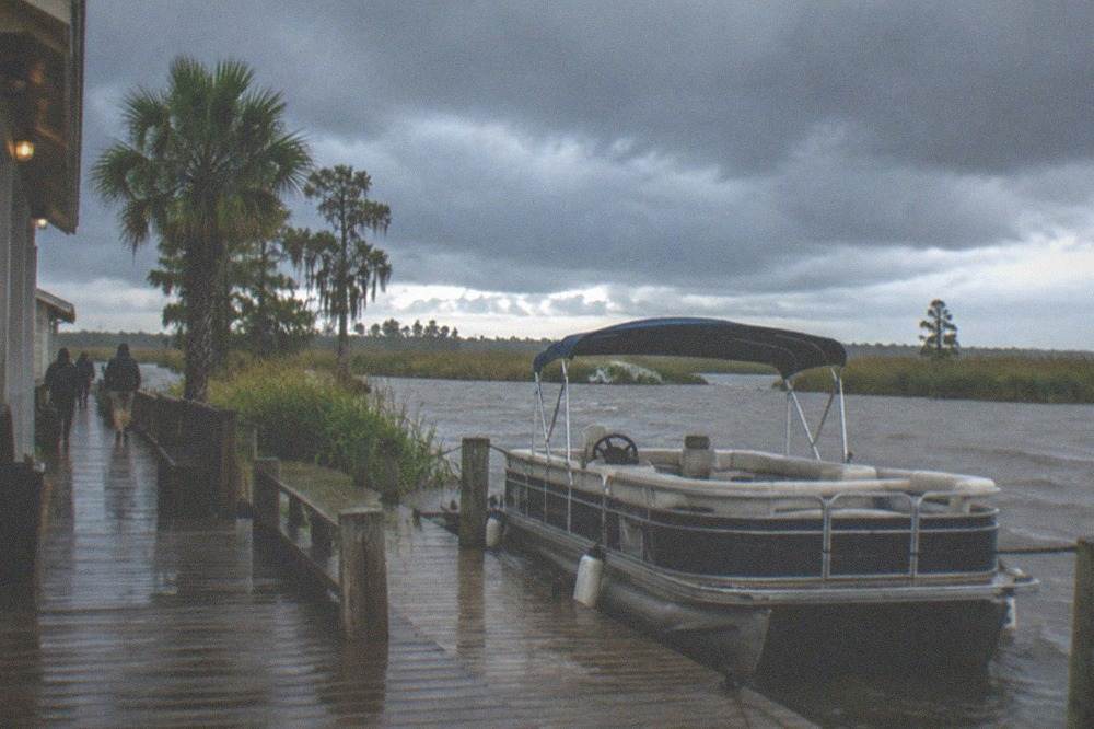 Dark storm clouds building over a marsh horizon with a swamp tour dock in the foreground